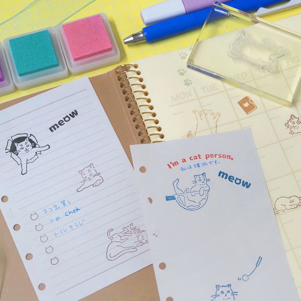 Notebooks with cat-themed illustrations and stationery items on a yellow surface