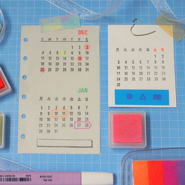 Two small calendars on a blue grid background with office supplies.