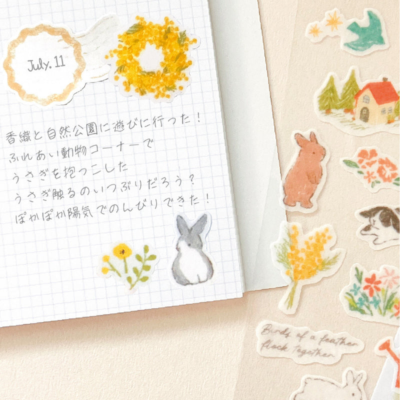 Notebook with decorative stickers of rabbits, flowers, and a house on a beige background.