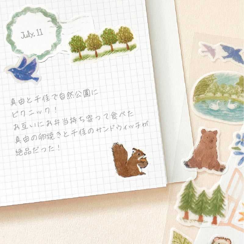 Notebook with nature-themed stickers including trees, a bird, a bear, and a squirrel.