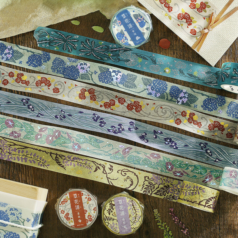 Decorative washi tapes with floral and nature-themed designs on a wooden surface.