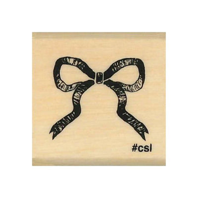 Wooden stamp with a black bow design and '#csi' text on a beige background