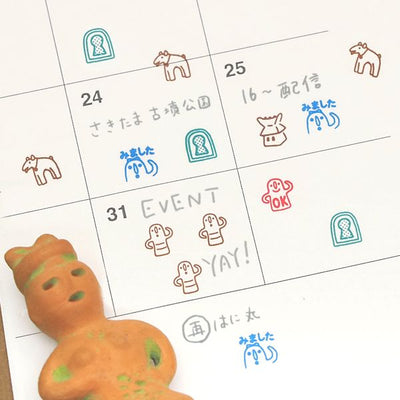 Calendar with hand-drawn stamps and a toy figure on a white background
