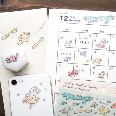 Calendar with cartoon illustrations of animals and a phone case with similar designs on a wooden surface.
