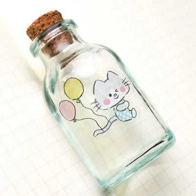 Glass bottle with cork lid containing a cartoon cat and balloons on a white background