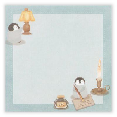 Notepad with penguin design, lamp, candle, and inkwell on a light blue background