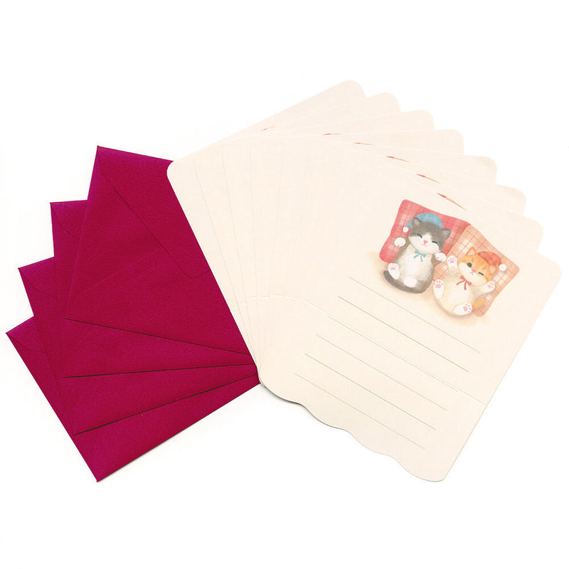 Set of pink envelopes and a beige letter pad with stationery items on a white background