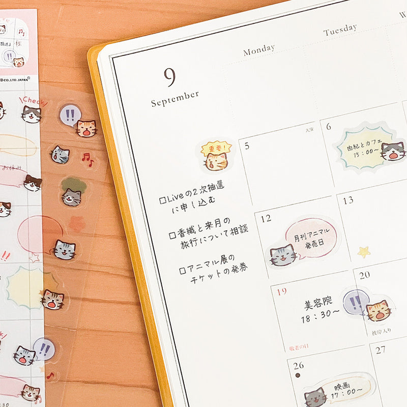 Calendar with cat-themed stickers on a wooden surface