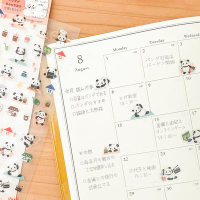 Calendar with panda-themed stickers on a wooden surface