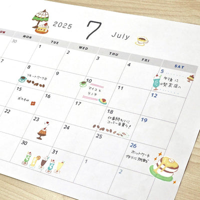 Calendar for July 2025 with cartoon illustrations on a wooden surface