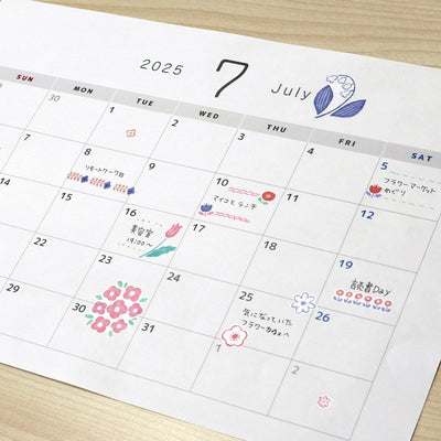 Calendar for July 2025 with decorative elements on a wooden surface