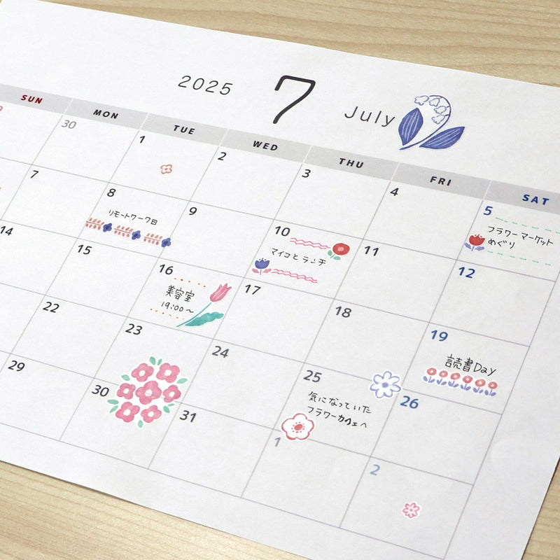 Calendar for July 2025 with decorative elements on a wooden surface