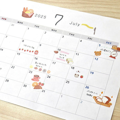 Calendar for July 2025 with cute illustrations on a wooden surface