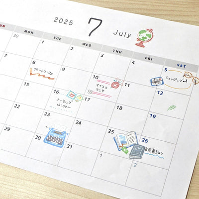 Calendar for July 2025 with various icons and notes on a wooden surface