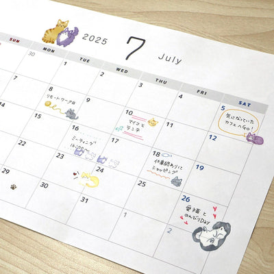 Calendar for July 2025 with cute animal illustrations on a wooden surface
