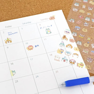 Calendar with cute animal stickers and a pen on a cork background