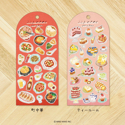 Two sticker sheets with food illustrations on a wooden surface