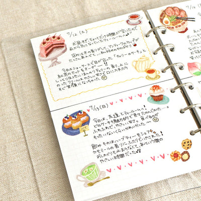 Notebook with illustrated food pages and text on a beige surface