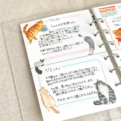 Open notebook with illustrated pages of cats on a textured surface