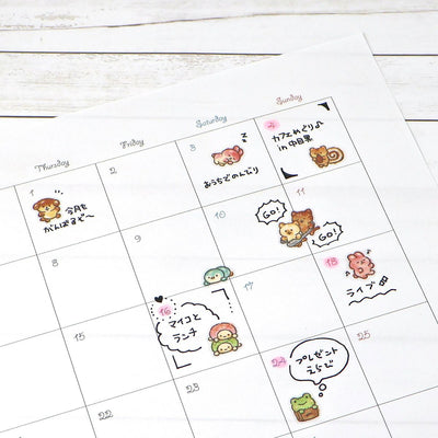 Calendar with cute animal illustrations and text on a white wooden surface