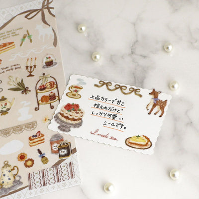 Decorative sticker sheet with illustrations of cakes and a deer on a marble surface.