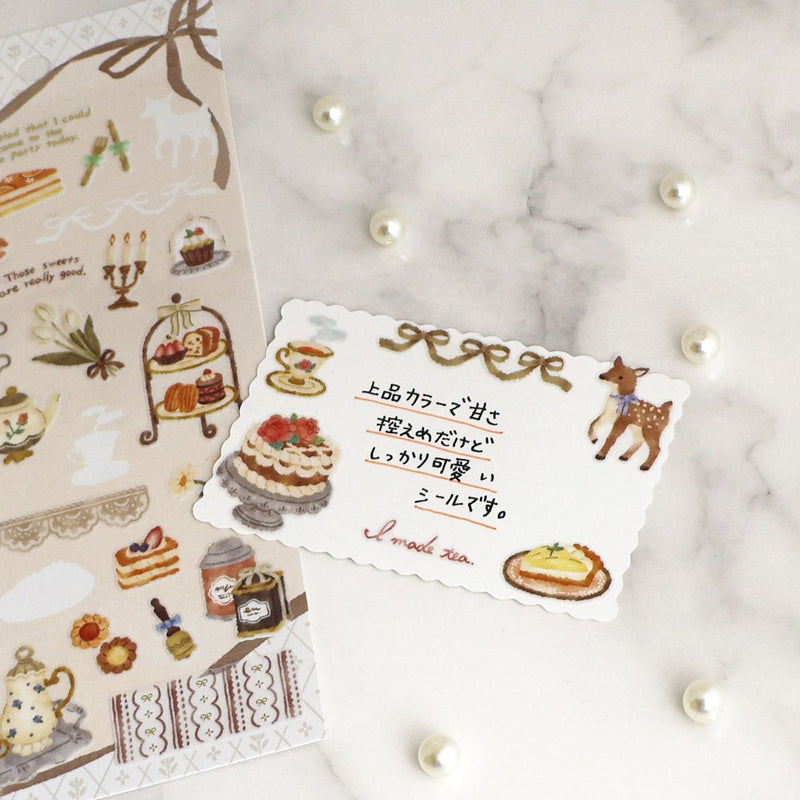 Decorative sticker sheet with illustrations of cakes and a deer on a marble surface.