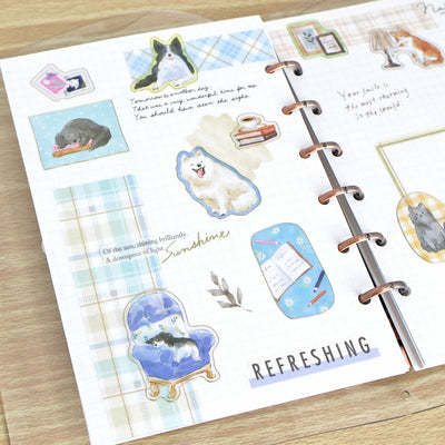 Planner with decorative stickers featuring animals and text on a wooden surface