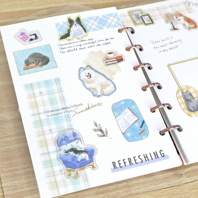 Planner with decorative stickers featuring animals and text on a wooden surface