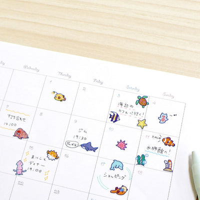 Calendar with cartoon sea creature stickers on a wooden surface