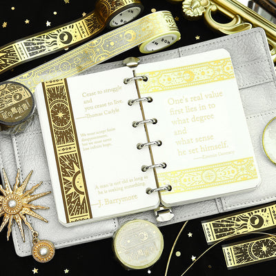 Decorative notebook with gold text and designs on a black background with decorative items.