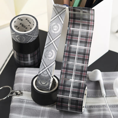 Plaid patterned tape and paper with a black and white design on a checkered surface.
