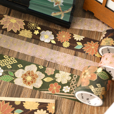 Decorative washi tape with floral and geometric patterns on a wooden surface.
