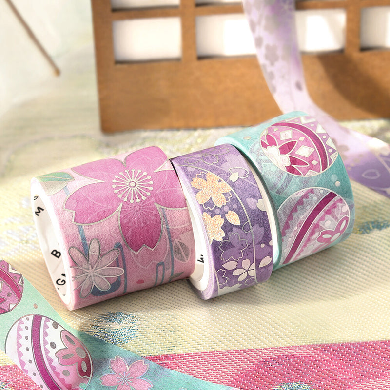 Three rolls of floral-patterned tape on a wooden surface.