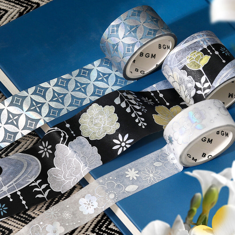 Decorative tape rolls with floral and geometric patterns on a blue surface.