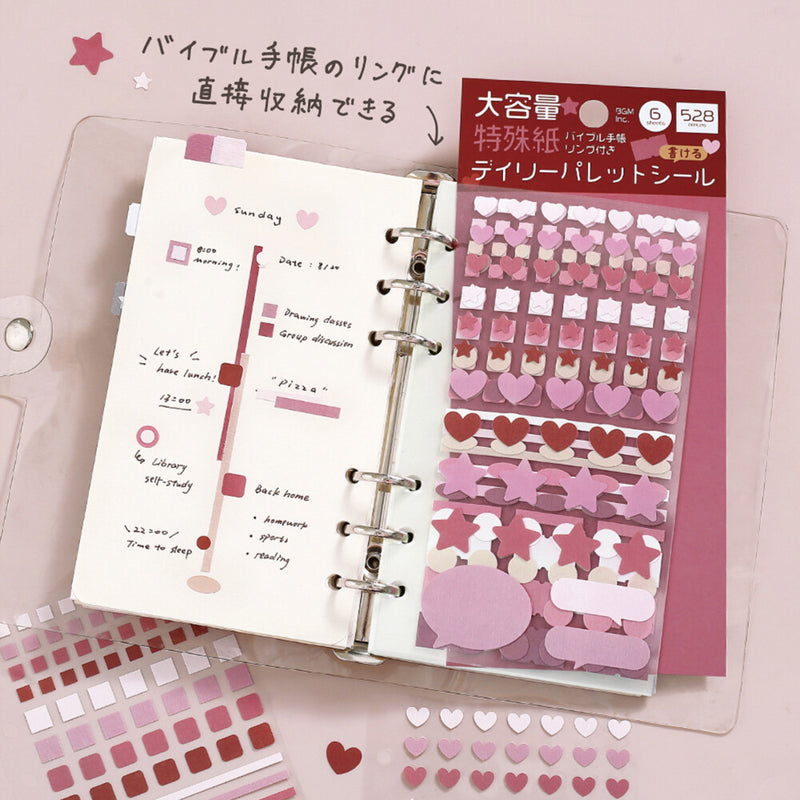 Open planner with pink stickers and a pink cover on a light pink background