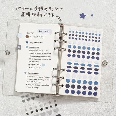 Open planner with notes and blue dot stickers on a light gray background