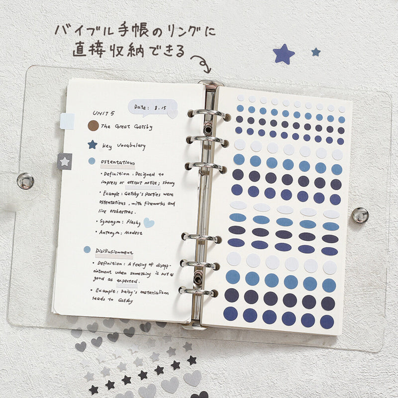 Open planner with notes and blue dot stickers on a light gray background