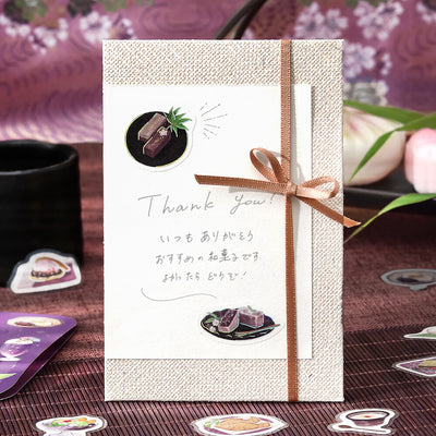 Gift card with a brown ribbon on a textured surface with decorative elements.