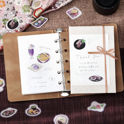 Open notebook with decorative pages and stickers on a textured surface