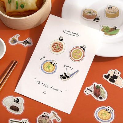 Stickers featuring panda bears and Chinese food on a red surface with a sheet of paper.