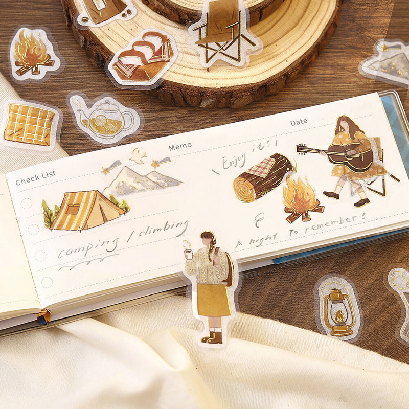 Sticker set with camping-themed designs on a wooden surface