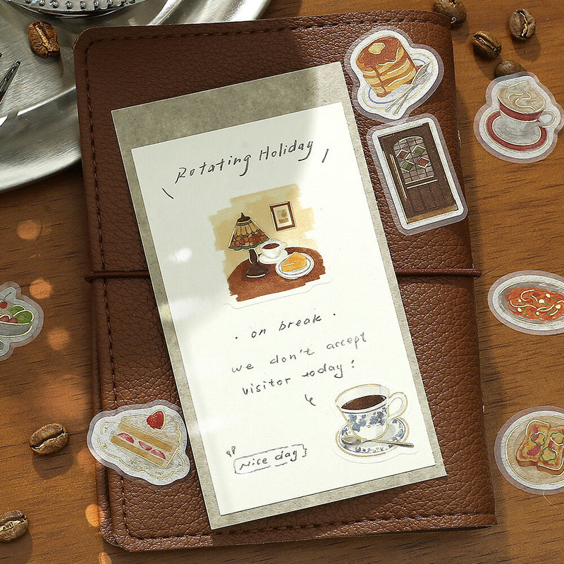 Brown leather notebook with a decorative card featuring illustrations of food and coffee on a wooden surface.
