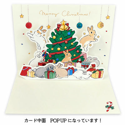 Christmas card with rabbits around a Christmas tree and presents.