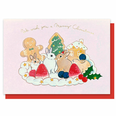 Christmas-themed card with bunnies, cookies, and trees on a pink background