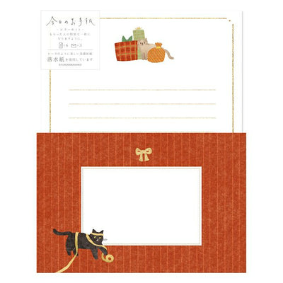 Stationery set with a black cat illustration on an orange envelope and lined paper.
